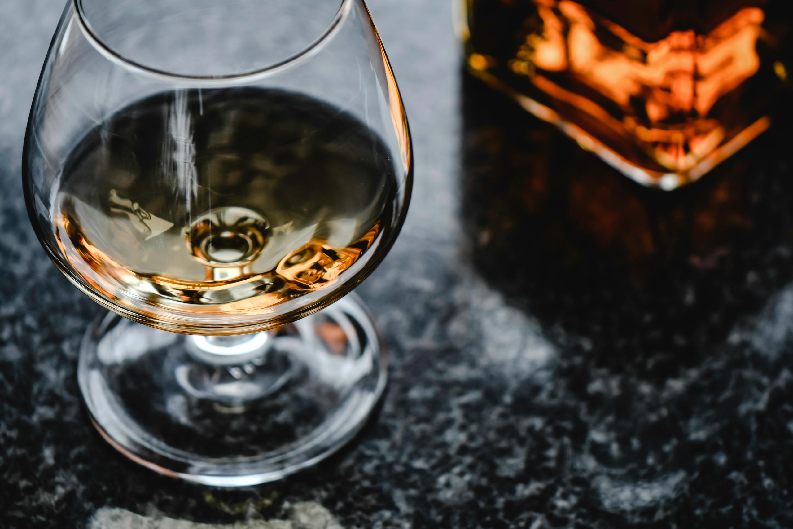 Close-up of cognac in a snifter glass on a marble surface with a warm, inviting tone.
