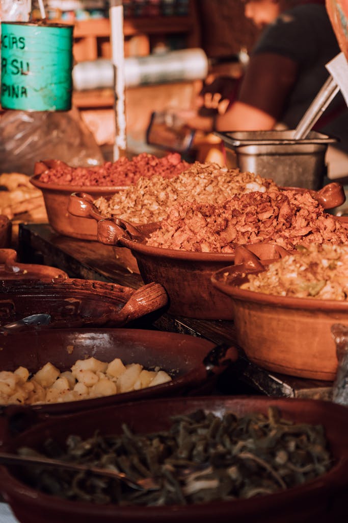 Close-up of traditional Mexican dishes served in rustic clay bowls at a market.